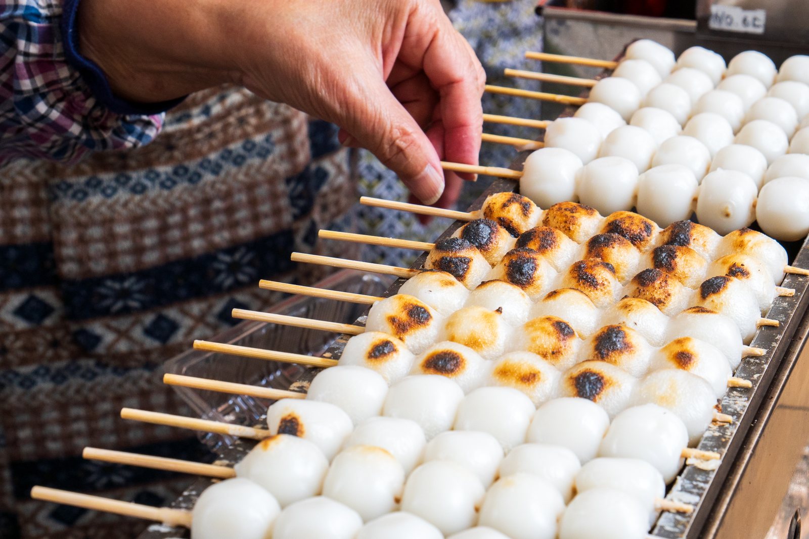 屋台の鉄板で焼かれるみたらし団子